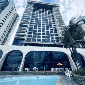 a large building with a pool in front of a hotel at Flat 10 andar no Golden Beach acesso direto a praia in Recife