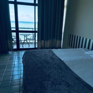 a bedroom with a bed and a view of the ocean at Flat 10 andar no Golden Beach acesso direto a praia in Recife