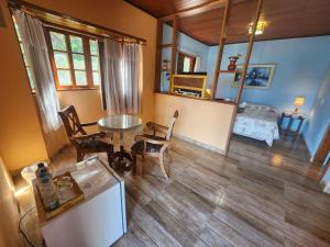 a kitchen and living room with a table and a bed at Chales Estrada de Chão in Monte Verde