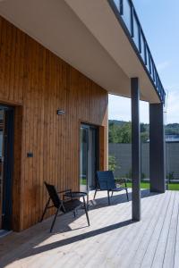 two chairs sitting on a deck next to a building at Villa Studenec in Banská Štiavnica
