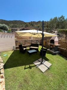 a patio with a table and an umbrella on the grass at Villa Orsola in Chia