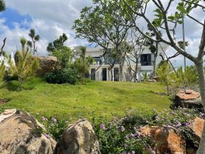 a house on a hill with flowers in the yard at Nhà Bên Đồi - The Hill House Villa in La Sơn