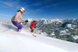 Due persone stanno sciando giù da una montagna innevata di Lutz Alpenblick B&B a Schattwald