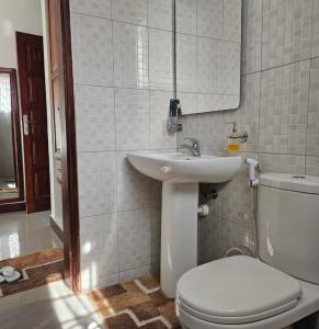 a white bathroom with a toilet and a sink at Revara Home in Dodoma +35 photos