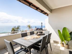 a dining room with a table and chairs and the ocean at Beachfront Apartment Shakas Rock - Martinique, Pool, Ocean Views in Ballito
