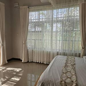 a bedroom with a bed and a large window at Revara Home in Dodoma