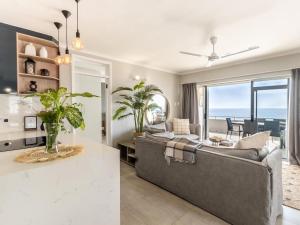a living room with a couch and a table at Beachfront Apartment Shakas Rock - Martinique, Pool, Ocean Views in Ballito
