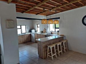a large kitchen with a counter and stools in it at Grootfontein Farm accommodation in Stilbaai