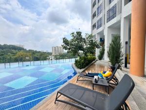 a man sitting in a chair next to a swimming pool at Homestay Abg Ipar in Putrajaya
