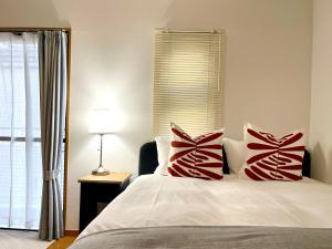 a bedroom with a bed with red and white pillows at 新宿一站5分钟-303-餐馆购物街-安静品质公寓-直达皇居秋叶原 in Tokyo