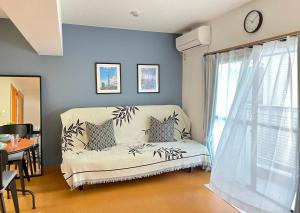 a living room with a couch and a clock on the wall at 新宿一站5分钟-303-餐馆购物街-安静品质公寓-直达皇居秋叶原 in Tokyo