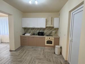 an empty kitchen with white cabinets and a stove at Pensiunea Cris in Pădureni +4 photos