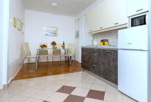 a kitchen with a refrigerator and a table with chairs at Apartments Kremenici in Malinska