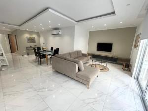 a living room with a couch and a tv and a table at Mellieha Spacious Apt back Terrace Prime Location in Mellieħa