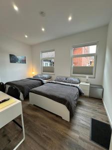 a bedroom with two beds and a desk and two windows at Gästehaus Bützfleth, Rad-Hotel, Arbeit & Privat, Bed & Breakfast, Elb Rad Wanderweg, Bäckerei & Gastro im Haus in Stade