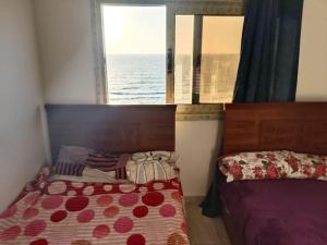Un dormitorio con una cama y una ventana con el mar. en luxury flat on blue meka beach, en Alejandría