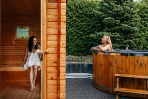 two women sitting in a hot tub in a cabin at APARTAMENTY VILLA PIGMALION - sauna, jacuzzi, parking, ogród in Kudowa-Zdrój