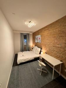- une chambre avec un lit, un bureau et un mur en briques dans l'établissement Zentrales Apartment Mehringdamm, à Berlin