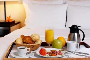 a tray with breakfast foods and a glass of orange juice at Art Museum Villa Hoi An in Hoi An