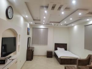 a bedroom with a bed and a tv and a couch at شقق مفروشه قارا in Qārā