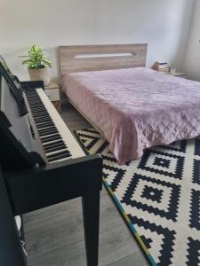 a bedroom with a bed and a piano and a rug at Charmante chambre bucolique - 2ᵉ en option in Chastre-Villeroux-Blanmont