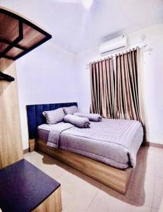 a bedroom with a bed with a curtain and a window at Kamiliya Homestay in Ngabean