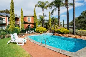 una piscina con 2 sillas de césped y una casa en Clare Country Club, en Clare