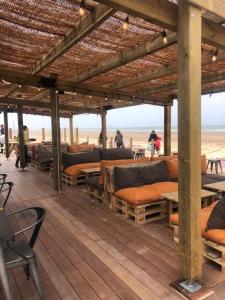 a wooden deck with beds and tables on the beach at FLAT Calais beach in Calais