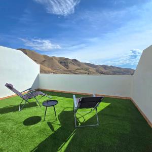 two chairs and a table on a balcony with grass at Casa Serena Alojamiento Rural in Enix