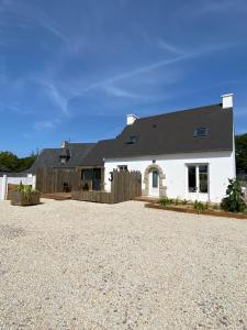 a white house with a black roof and a gravel driveway at En vacances Simone ! in Plurien