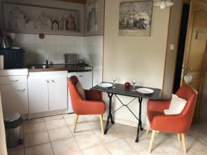a kitchen with a table and two chairs with wine glasses at Le clos de la Pommeraie maisonnette in Carly