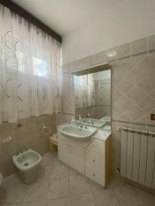 a bathroom with two sinks and a toilet and a mirror at Appartamento pineta in Viareggio