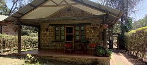 a small brick house with a porch and chairs at Kilimanjaro Lodge Cabins in Moshi