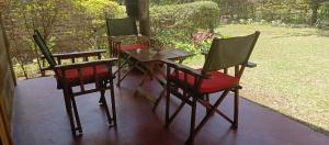 three chairs and a table on a porch at Kilimanjaro Lodge Cabins in Moshi