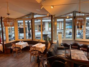 a restaurant with tables and chairs and windows at Grichting Hotel & Serviced Apartments in Leukerbad