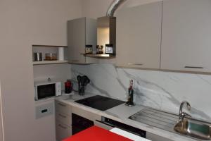 a white kitchen with a sink and a microwave at Da Alessandro in Biella