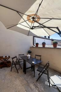 a patio with a table and chairs and an umbrella at La CASA al CENTRO in LʼAquila