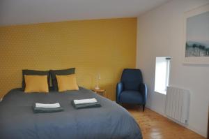 a bedroom with a bed and a blue chair at Maison du vigneron Saint-Martin in Cournon-dʼAuvergne