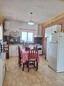 eine Küche mit einem Tisch mit Stühlen und einem weißen Kühlschrank in der Unterkunft Casa Reyes in Reyes
