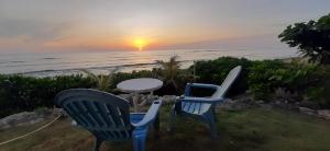 two chairs and a table with the sunset in the background at BlueWave Surf Stay in San Isidro