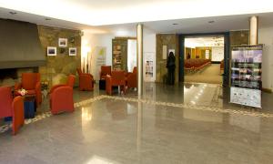a lobby with orange chairs and a waiting room at Hotel y Cabañas Le Village in San Martín de los Andes