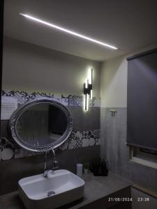 a bathroom with a sink and a round mirror at olivegrove in Sidari
