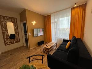 een woonkamer met een zwarte bank en een tv bij Apartament BELMARE F522 in Międzyzdroje