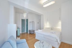 a white bedroom with a white bed and a blue couch at Clock Tower Arachova in Arachova