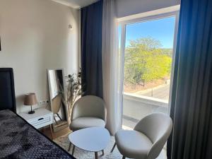 a bedroom with a bed and two chairs and a window at Venus Apartment in Kŭrdzhali