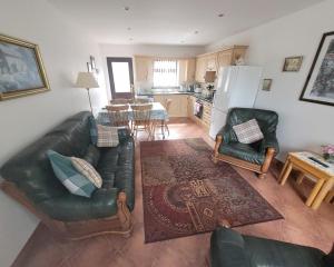 ein Wohnzimmer mit einem Sofa und Stühlen sowie eine Küche in der Unterkunft Drumgart Self Catering Cottage in Carrickfergus