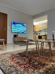 a living room with two tables and a tv on a wall at Adagio, JIMA winery luxury apartments in Ioannina