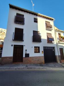 a white building with black doors and windows at Casa Taracea del Chapiz in Granada