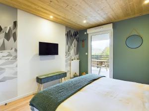 une chambre avec un lit et une télévision au mur dans l'établissement Panorama MontBlanc, à Domancy