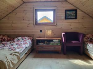 a bedroom with a bed and a chair in a cabin at Mazury Przyjazny Dom w Leleszkach z gorącą balią in Leleszki